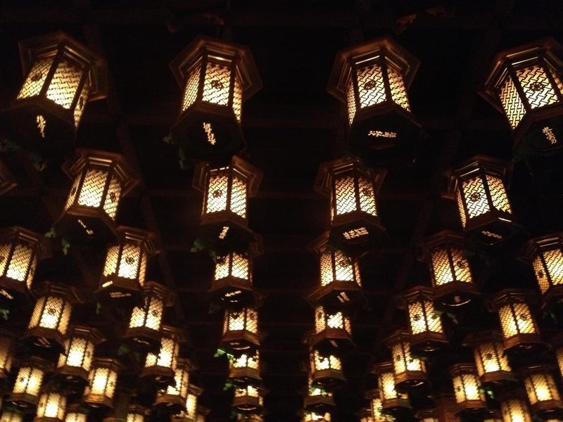 Candle-lit lanterns attached to a ceiling arranged in regular rows, seen from underneath.jpg