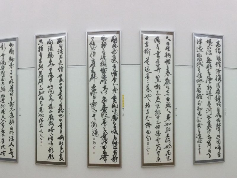 Five framed handpainted kanji sheets side by side on a wall.jpg