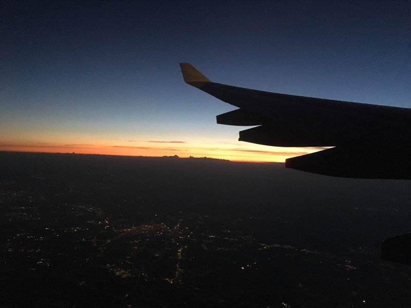 Sunset from the air, with dark orange and blue tones, and the contour of a plane wing in the foreground.jpg